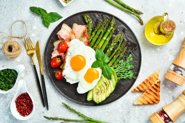 Kahvaltıda Çırpılmış Yumurta Kuşkonmaz Pastırma Avokado Siyah Taştan Bir Tabakta — Stok fotoğraf