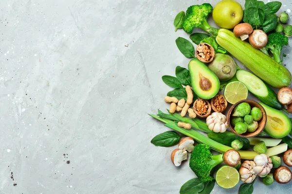 Food for heart health. Green vegetables, fruits, nuts and mushrooms. On a gray stone background. Top view.