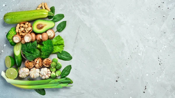 Food for heart health. Green vegetables, fruits, nuts and mushrooms. On a gray stone background. Top view.