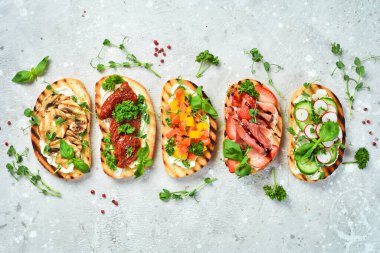 Ev yapımı bruschettalar ve sebzeli, peynirli, mantarlı ve jambonlu sandviçler. Sandviç. Taş bir arka planda.