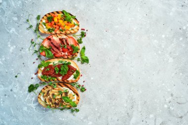Ev yapımı bruschettalar ve sebzeli, peynirli, mantarlı ve jambonlu sandviçler. Sandviç. Taş bir arka planda.