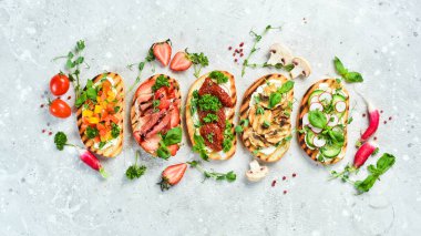 Sebzeli, peynirli, mantarlı ve jambonlu nefis ev yapımı bruschettalar. Sandviç. Taş zeminde. Üst görünüm.