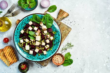 Pancar salatası, tofu peyniri, ıspanak ve kabak çekirdeği. Sağlıklı beslenme kavramı. Taş zeminde. Üst görünüm.