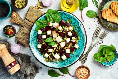 Pancar salatası, tofu peyniri, ıspanak ve kabak çekirdeği. Sağlıklı beslenme kavramı. Taş zeminde. Üst görünüm.
