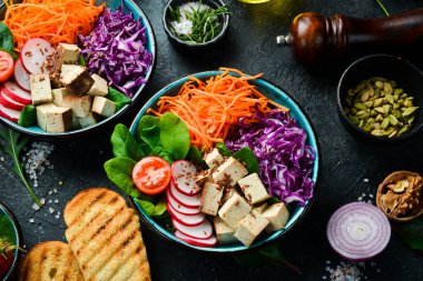 Tofu peyniri, ıspanak, lahana, turp ve havuçla detoks Buda kasesi. Beslenme konsepti. Taş bir arka planda.