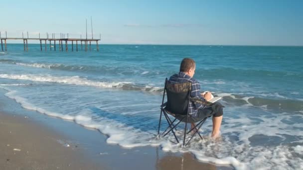 Άνθρωπος ανάγνωση βιβλίο στην παραλία — Αρχείο Βίντεο