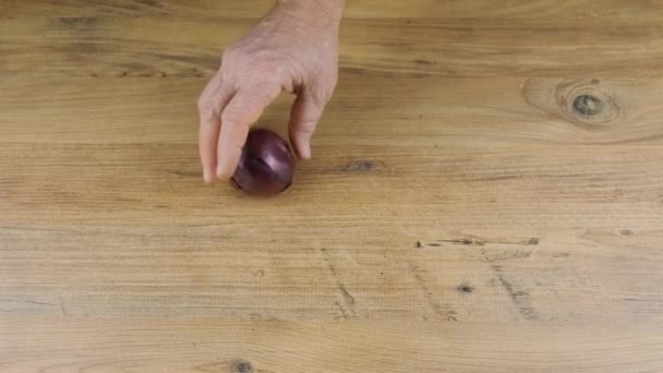 사람은 퍼플 온 이온 나무 식탁에 앉는다. 신선 한 양파 — 비디오