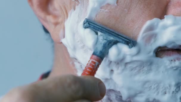 Przerażony człowiek krwawienia podczas golenia twarzy z ostrzem — Wideo stockowe