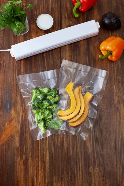 Vacuum cleaner with vacuum bags with broccoli and pumpkin slices with fresh vegetables on a dark wooden table. Copy space text