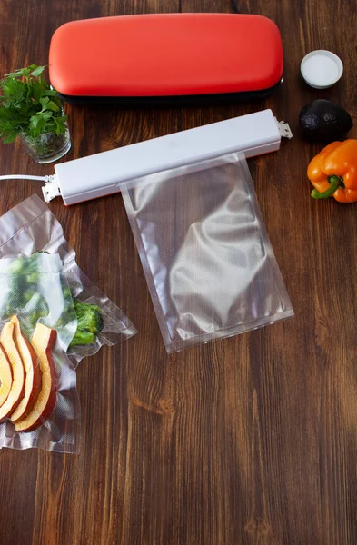 Two vacuum cleaners for food on a wooden table with a vacuum bag. Copy space text