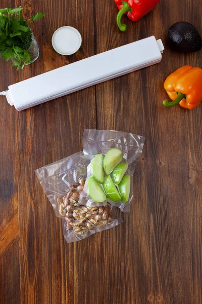 Vacuum cleaner with vacuum bags with slices of green apples and nuts with fresh vegetables on a dark wooden table. Copy space text