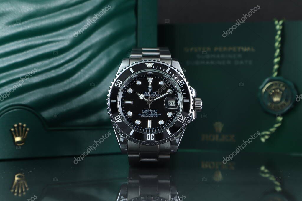 The Rolex vintage wristwatch ceramic bezel model black oyster perpetual submariner date 39 mm display on mirror shelf with background of Rolex green box crown logo , coin and manual book