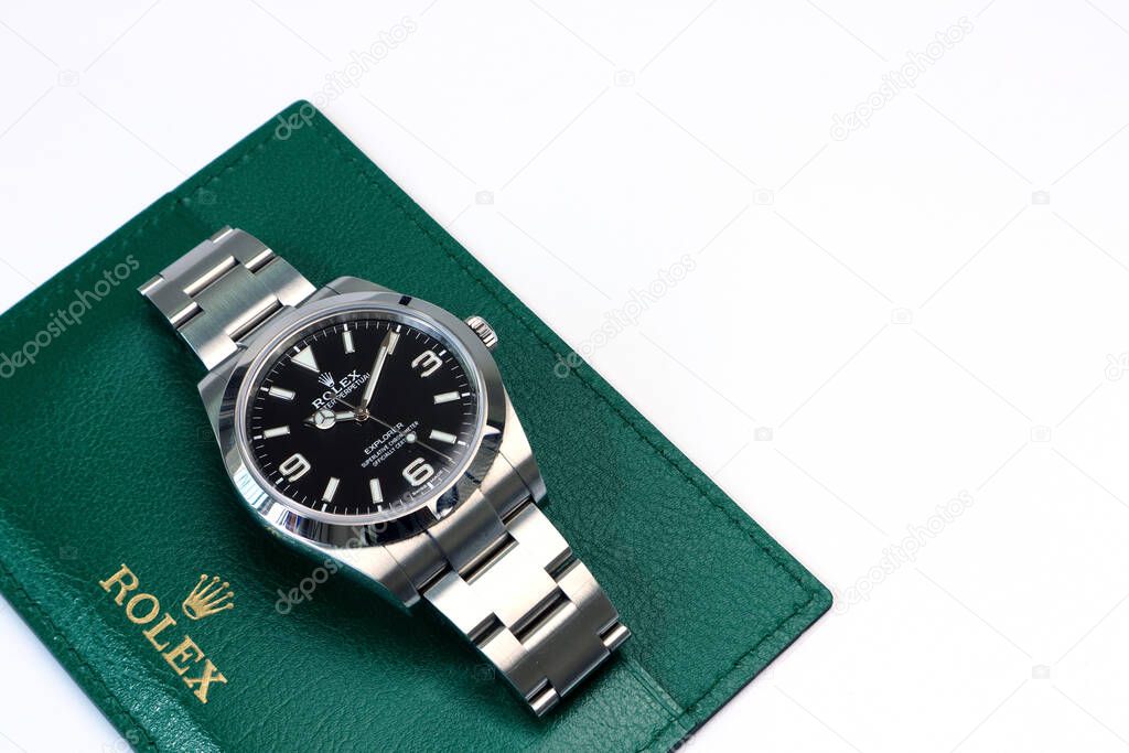 The Rolex vintage wristwatch model oyster perpetual explorer I display on the green leather of Rolex crown logo on white background