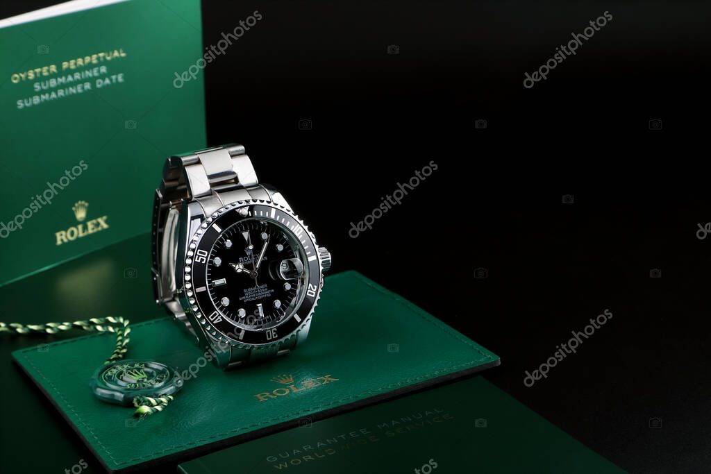 Rolex vintage wristwatch ceramic bezel model black oyster perpetual submariner date is on black shelf with background of Rolex green box crown logo , coin manual book