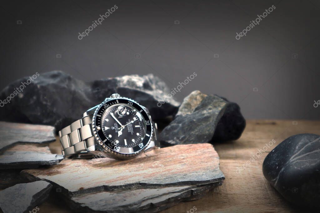 The Rolex vintage wristwatch ceramic bezel model black oyster perpetual submariner date 39 mm display on the wooden table with some stones