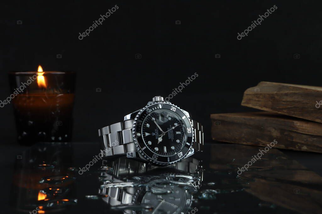 The Rolex vintage wristwatch model oyster perpetual explorer I 39 mm display on the black stone table with background of flashlight, camera lens, and wooden stacks