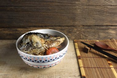 Lezzetli soya sosu çorbası ahşap masada servis edilir kaşık, yemek çubukları ve bambu hasırla geleneksel Japon restoranında ahşap duvarın arka planında.