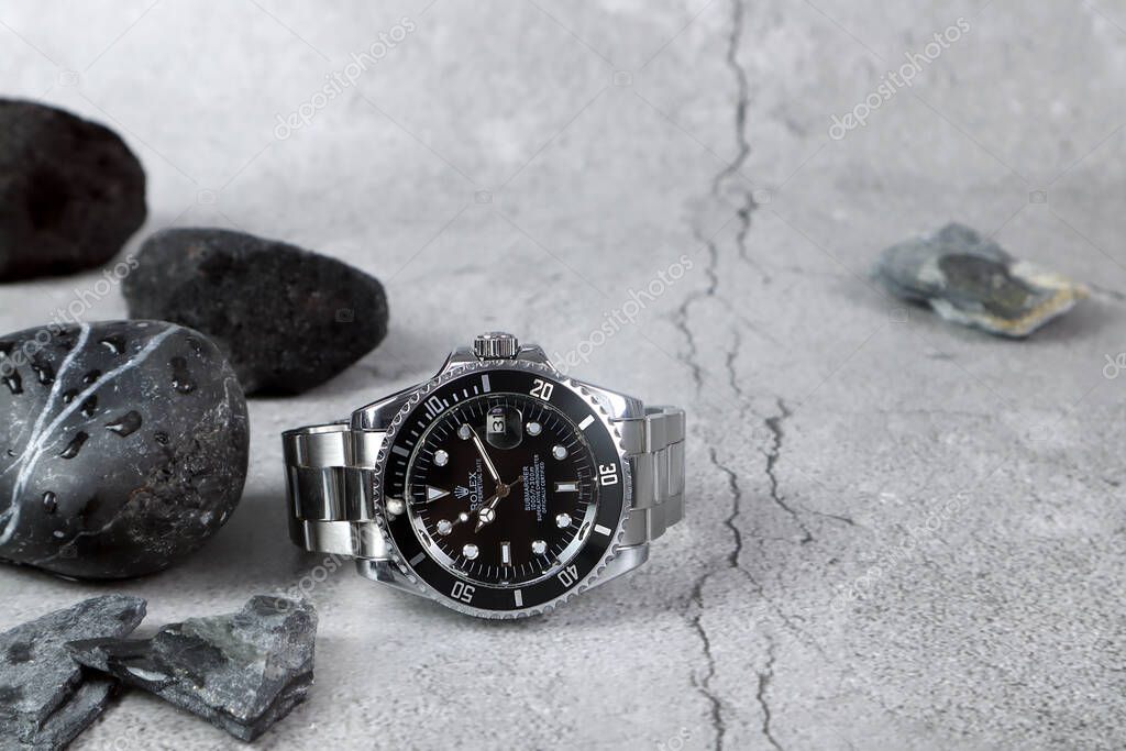 The Rolex vintage wristwatch ceramic bezel model black oyster perpetual submariner date 39 mm display on the stone table with small stones in the luxury watch shop