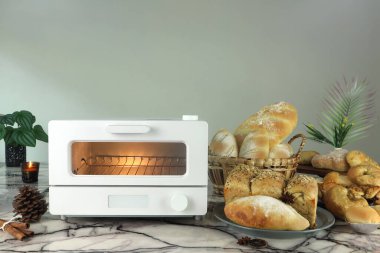 Beyaz modern tasarım tost makinesi masanın üstünde. Noel partisi sırasında mutfak odasının arka planında ev yapımı tost ekmeği var.