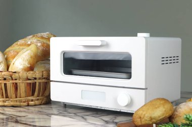 Beyaz modern tasarım tost makinesi masanın üstünde. Noel partisi sırasında mutfak odasının arka planında ev yapımı tost ekmeği var.