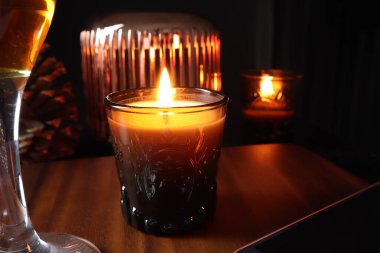 the burning luxury aromatic scented candle glass on the wooden table with glass of champagne and mobile phone in the living room to creat relax ambient during christmas new year party celebration