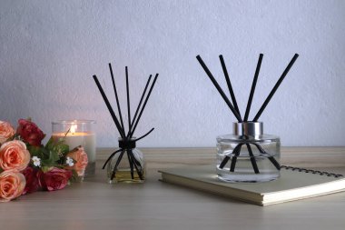 Lüks kokulu kamış aromalı difüzyon şişesi ahşap masa üzerinde romantik yaratmak için mum ve yatak odasının atmosferini gevşetmek için sabah beyaz çimento duvarlı arka planda Sevgililer Günü için