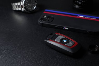 BMW serisi 3 modelinin anahtar (anahtarsız giriş sistemi) cep telefonu bmw m3 çanta ve bilek saati ile siyah ahşap tablo üzerindedir.