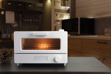 Beyaz modern tasarım tost makinesi kahverengi ahşap masanın üzerinde. Kahvaltı sırasında mutfak odasının arka planında.