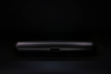 Modern tasarım kablosuz bluetooth hoparlör ya da ses çubuğu, siyah duvarlı siyah masanın üzerindedir.