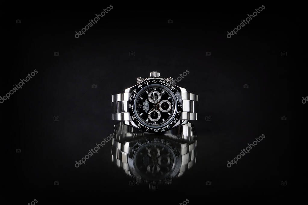 Rolex wristwatch model daytona oyster perpetual superlative chronometer with black ceramic bezel stainless steel body on black table with black wall background at the authorized dealer watch shop