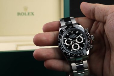 Rolex Kol Saati modeli kozmograf Daytona İstiridye Daimi süper kronometre Siyah seramik bezel paslanmaz çelik gövde ile sağ arka planda yeşil Rolex paket kutusu ile