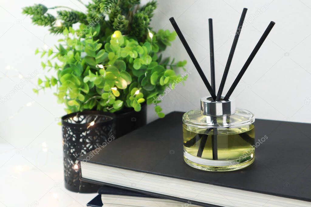luxury aroma scent reed diffuser glass bottle is on white table with books to creat romantic and relax ambient in bedroom with white cement wall background in the morning for happy valentine day