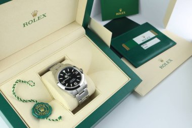Rolex wristwatch explorer I model is inside the green leather box of Rolex wristwatch which is on white table with service book and serial number card in authorized dealer Rolex shop