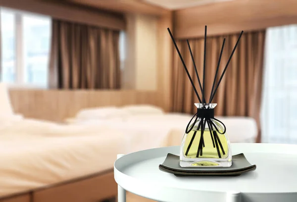 luxury aromatic scent of reed diffuser glass bottle is used as room freshener on the white metal table in the bedroom to creat relax and romantic ambient with background of nice bed on valentine day