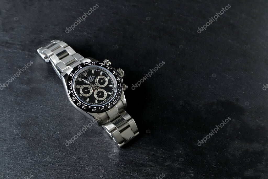 Rolex wristwatch model cosmograph daytona oyster perpetual superlative chronometer with black ceramic bezel stainless steel body display on black stone table in authorized dealer shop