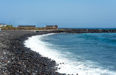 Puerto de la Cruz, Tenerife, Kanarya Adaları 'nda güneşli bir günde siyah kumlu bir sahil. İspanya