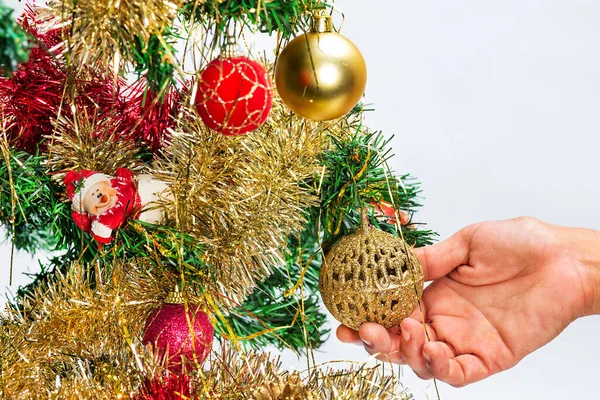 手のクローズアップは クリスマスツリーに黄金のボールを配置します 白地に — ストック写真