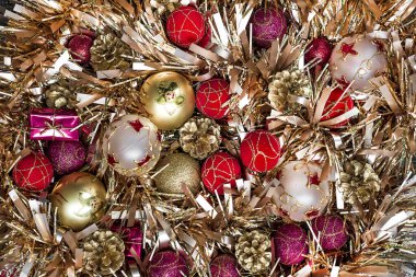 Altın çelenkler ve renkli toplarla süslenmiş Noel süsü. Kapat.