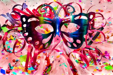 carnival and party mask with confetti and streamers on pink background