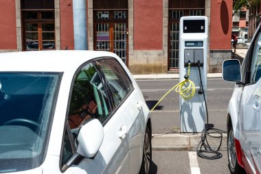 Güneşli bir günde modern bir benzin istasyonunda elektrikli araba şarj ediliyor.
