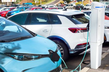 Güneşli bir günde modern bir benzin istasyonunda elektrikli araba şarj ediliyor.