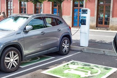 Güneşli bir günde modern bir benzin istasyonunda elektrikli araba şarj ediliyor.