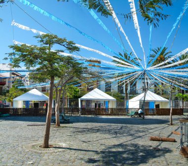 Şehrin meydanı, arka planda beyaz kulübelerle şenlikleri başlatmaya hazırlanıyor.