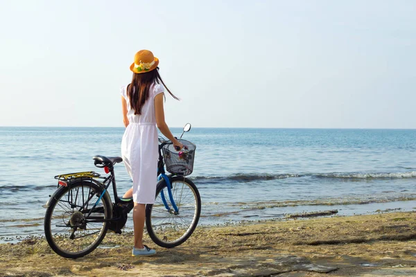 穿着白色长发 戴着草帽 在海滨骑自行车的女孩 后视镜 — 图库照片