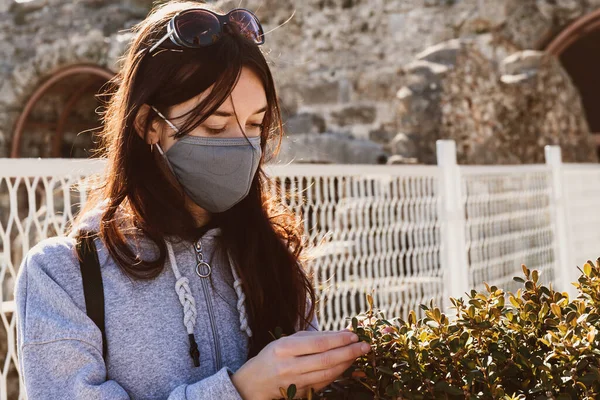 Sokakta salgın sırasında maske takan uzun saçlı yalnız ve güzel bir genç kadın yürüyor. Yakın çekim..