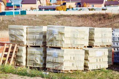 İnşaat alanında sarı tuğla ambalajı. Bir ev inşaatı için inşaat malzemeleri. Yakın plan..