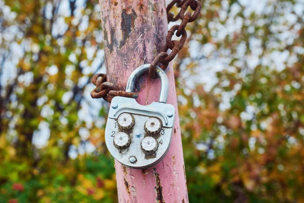An old metal combination lock on a rusty chain. Close-up, macro