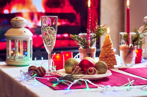 Kırmızı mumlar, ışıklar, altın toplar, masada Noel süslemeleri.