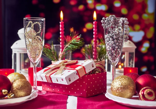 Kırmızı mumlar, ışıklar, altın toplar, masada Noel süsleri. Yakın çekim, seçici odaklanma.