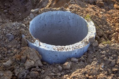 Construction of a septic tank sewer well. A concrete ring in the ground. Close-up.